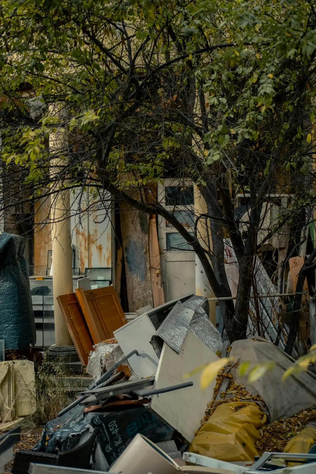 Pile of yard debris, furniture pieces, and bulk junk outside a property.